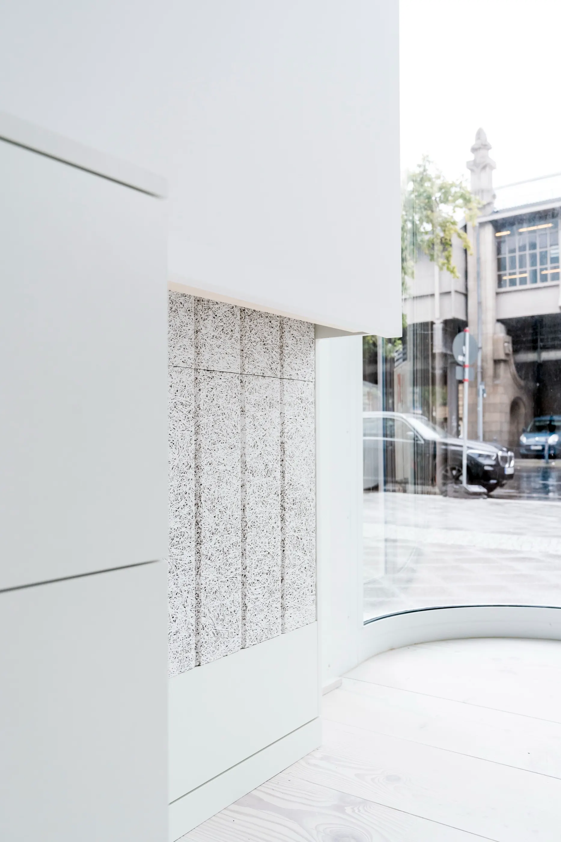 White joinery beside a granite-clad recess, daylight from the street front