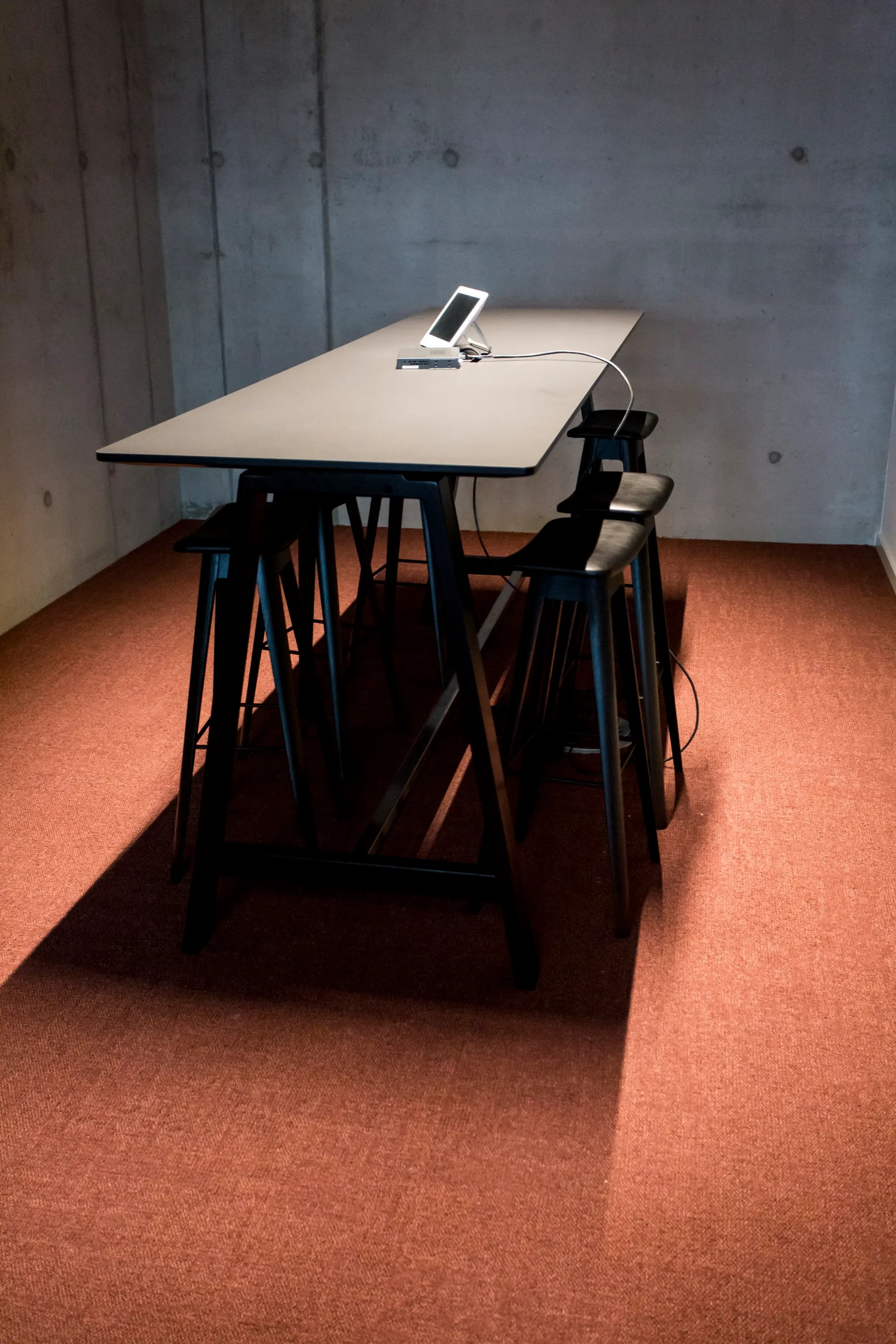 High table with stools against a concrete wall