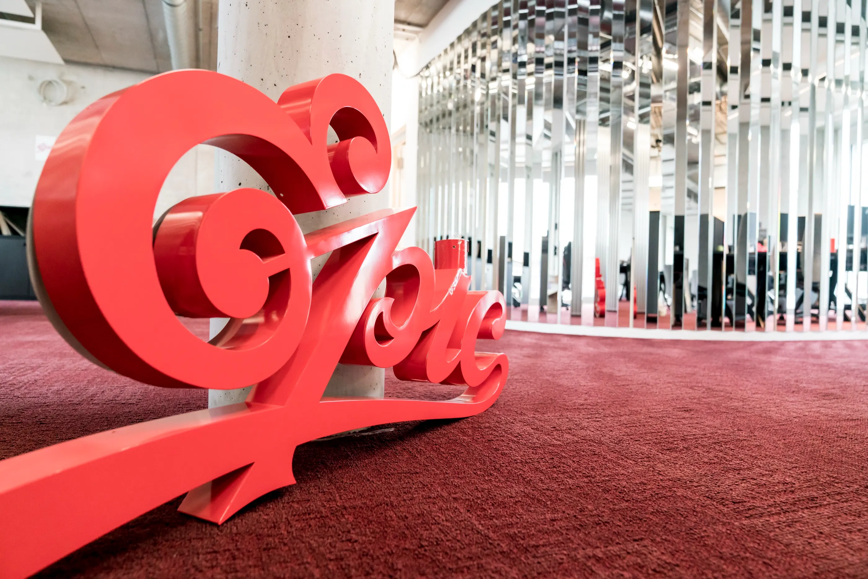 Red script sculpture on the office floor, mirrored ceiling behind it