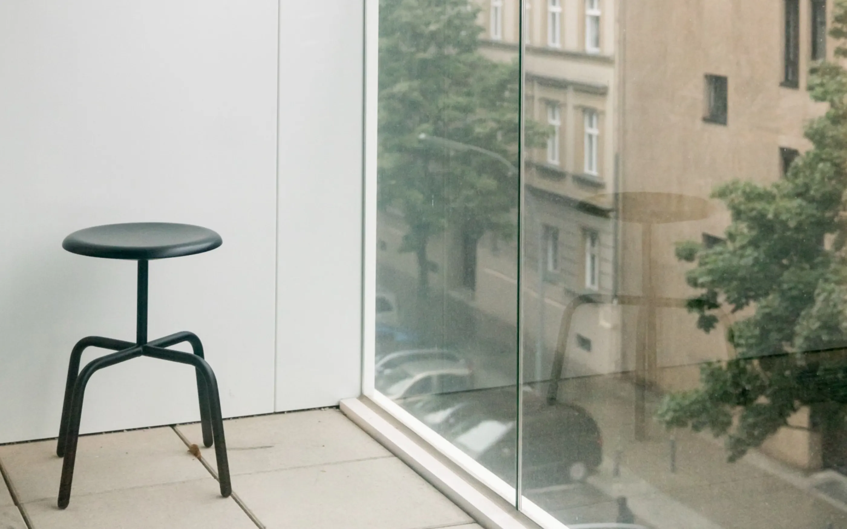 Stool at the window front, the street visible through the glazing