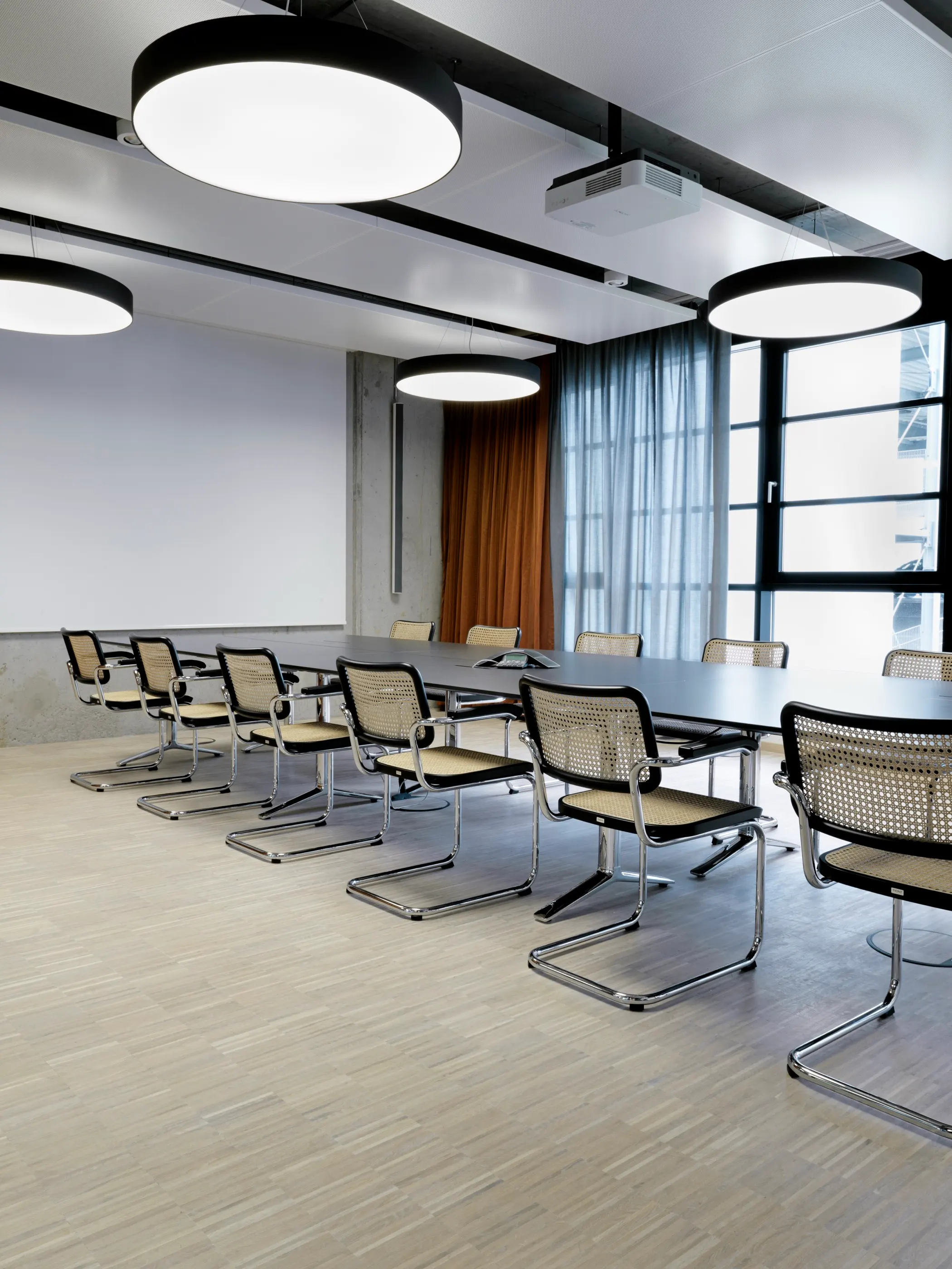 Conference room with a long table, cantilever chairs and drum pendants